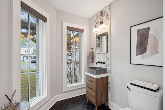 bathroom with baseboards, toilet, and vanity