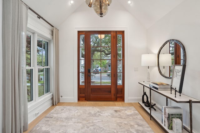 foyer entrance with light wood-style flooring, plenty of natural light, and vaulted ceiling
