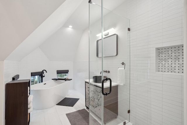 full bath with a stall shower, tile patterned floors, vaulted ceiling, a freestanding bath, and tile walls