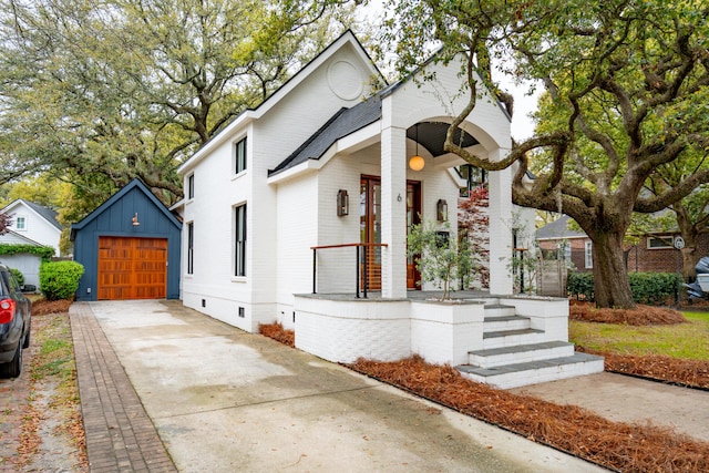 view of front facade featuring crawl space, driveway, a detached garage, and an outbuilding