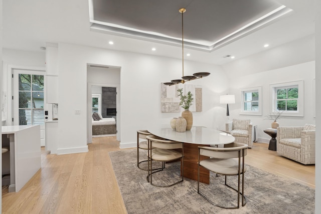dining area with a tray ceiling, baseboards, light wood-style floors, and recessed lighting