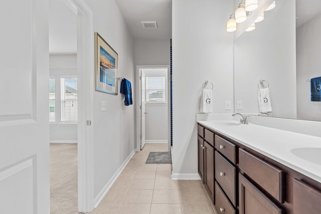 bathroom with tile patterned flooring, vanity, and a healthy amount of sunlight