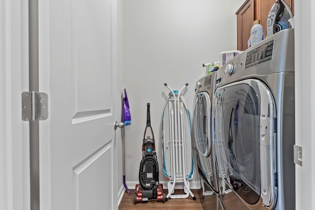 laundry room featuring cabinets, wood-type flooring, and washing machine and dryer