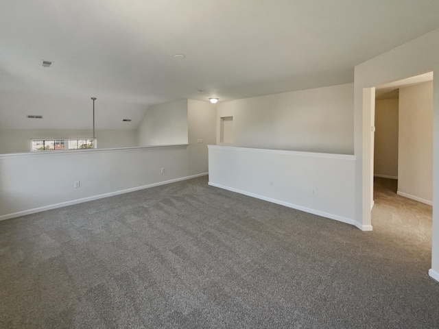 carpeted empty room with vaulted ceiling