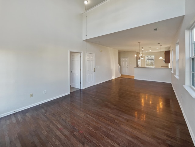 unfurnished living room with dark wood-type flooring and a notable chandelier