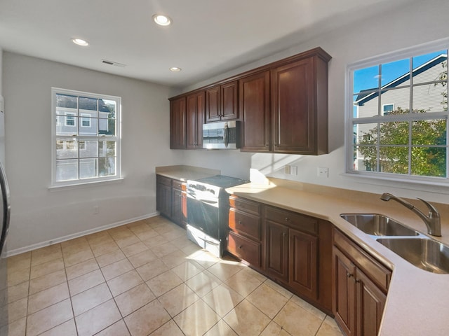 kitchen featuring electric stove, sink, light tile patterned flooring, and plenty of natural light