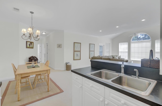 kitchen featuring white cabinetry, an inviting chandelier, decorative light fixtures, and sink