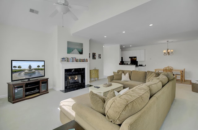 carpeted living room featuring ceiling fan with notable chandelier and a fireplace