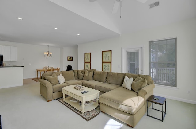 carpeted living room featuring ceiling fan with notable chandelier