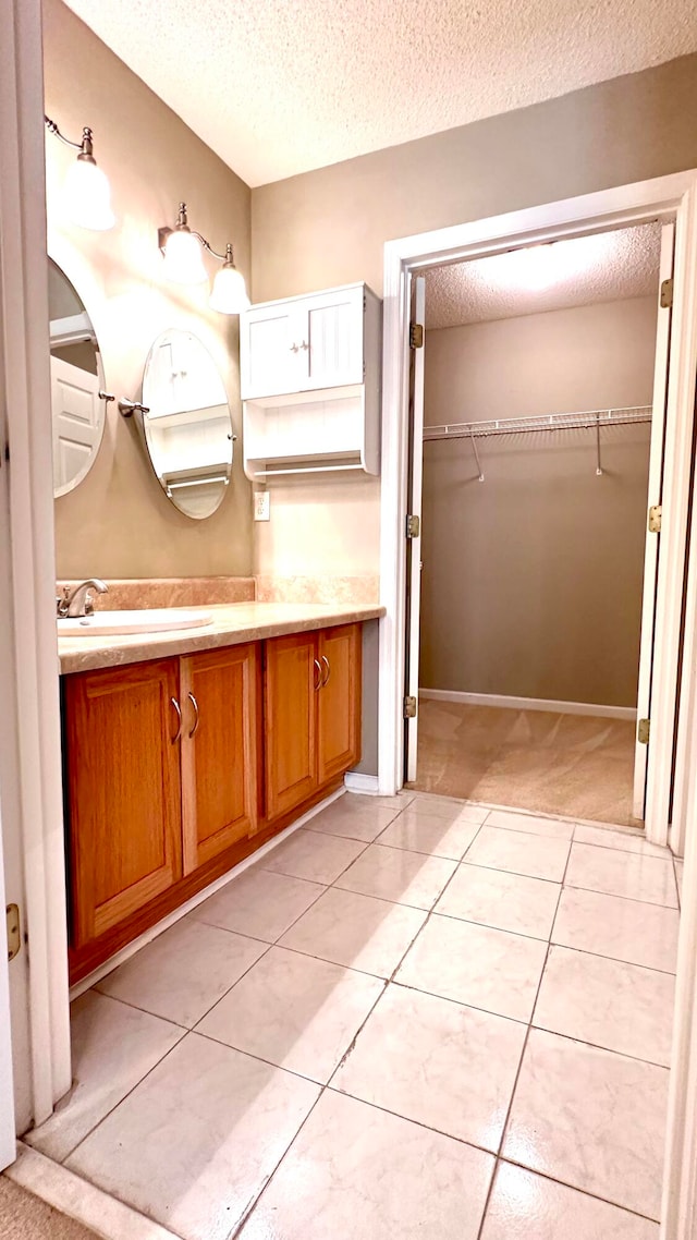 bathroom with tile patterned flooring, vanity, and a textured ceiling