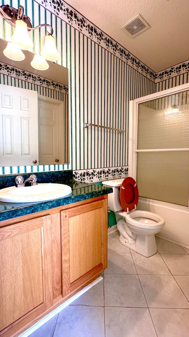 full bathroom with vanity, bath / shower combo with glass door, tile patterned floors, toilet, and a textured ceiling