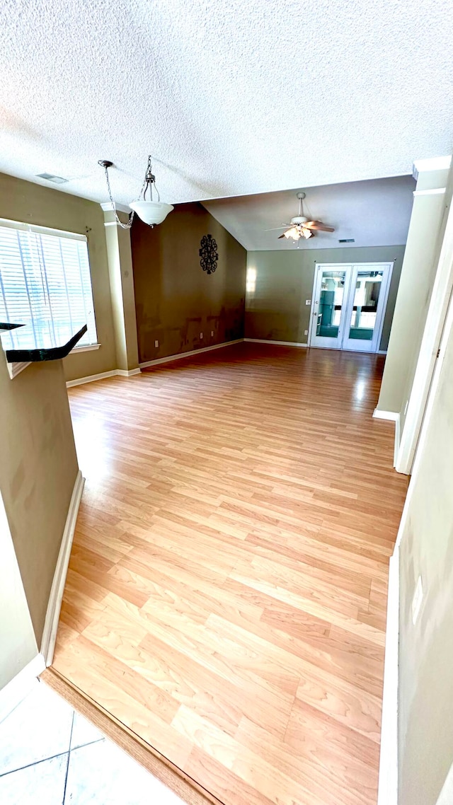 unfurnished living room with lofted ceiling, light hardwood / wood-style floors, a textured ceiling, and ceiling fan