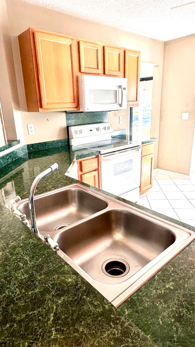 kitchen with a textured ceiling, sink, and white appliances