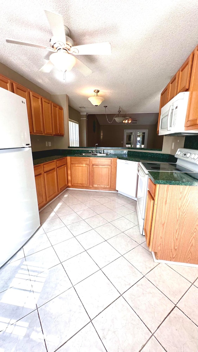 kitchen with ceiling fan, white appliances, sink, kitchen peninsula, and a textured ceiling