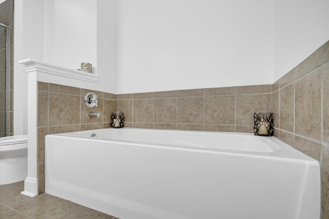 bathroom with toilet, tile patterned flooring, and a bath