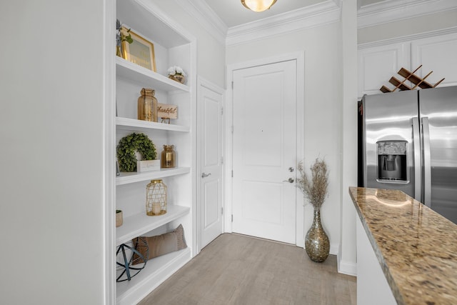 interior space featuring crown molding, built in features, stainless steel refrigerator with ice dispenser, light stone countertops, and light wood-type flooring