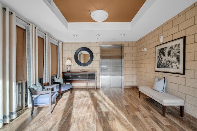 sitting room featuring a raised ceiling, hardwood / wood-style flooring, and elevator