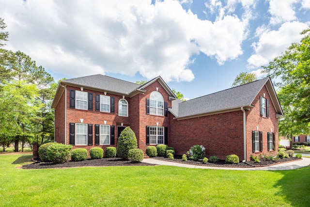 view of front facade featuring brick siding, roof with shingles, and a front lawn