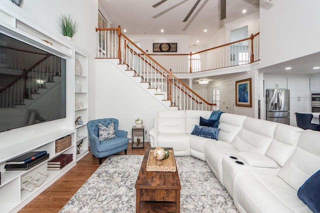 living room featuring recessed lighting, a ceiling fan, a high ceiling, wood finished floors, and stairway