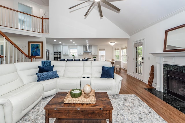 living area featuring recessed lighting, a high end fireplace, wood finished floors, a ceiling fan, and crown molding