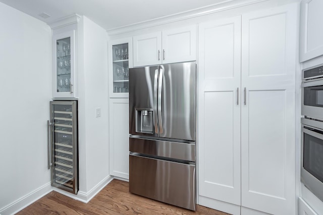 kitchen with wood finished floors, glass insert cabinets, stainless steel appliances, white cabinets, and wine cooler