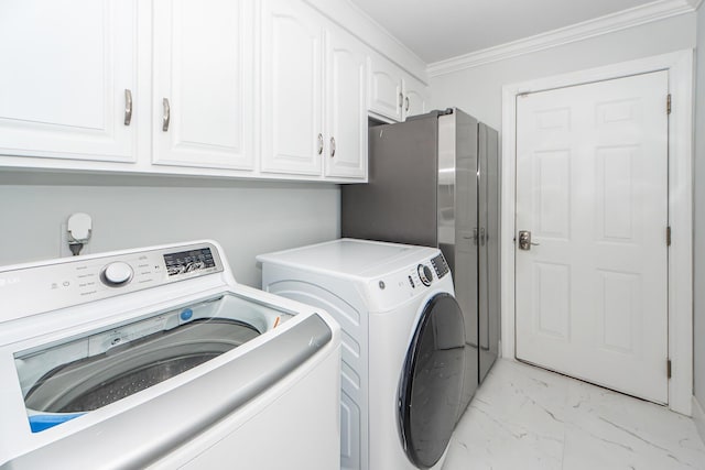 clothes washing area featuring marble finish floor, crown molding, washing machine and clothes dryer, and cabinet space