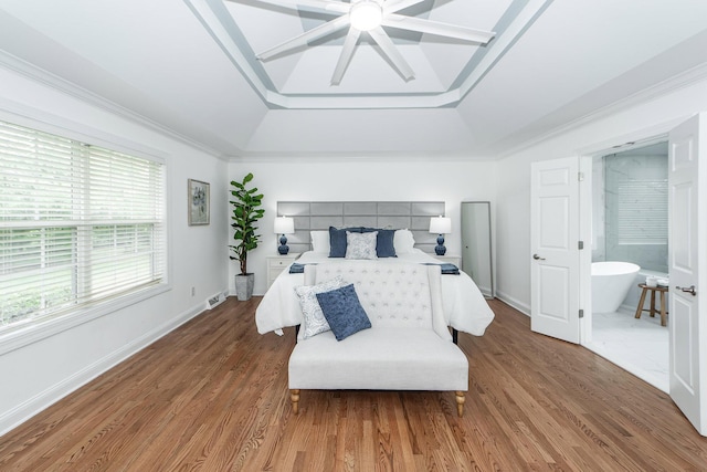 bedroom featuring crown molding, a ceiling fan, wood finished floors, a tray ceiling, and baseboards