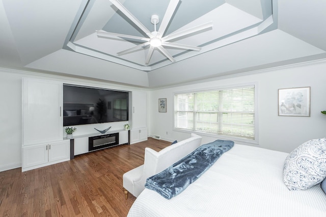 bedroom with ceiling fan, dark wood-type flooring, and a raised ceiling