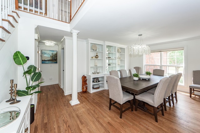 dining room featuring baseboards, decorative columns, a chandelier, and light wood-style floors