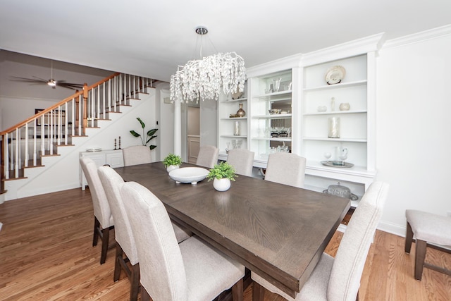 dining room with light wood-style floors, stairway, baseboards, and ceiling fan with notable chandelier