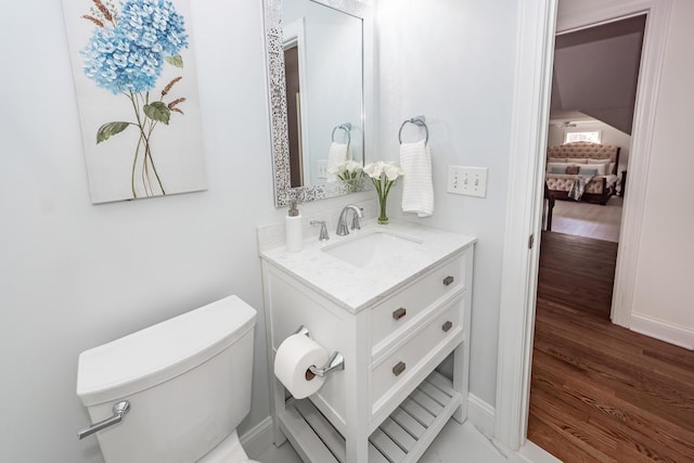 bathroom featuring baseboards, wood finished floors, vanity, and toilet