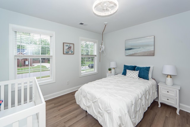 bedroom with baseboards, wood finished floors, and visible vents