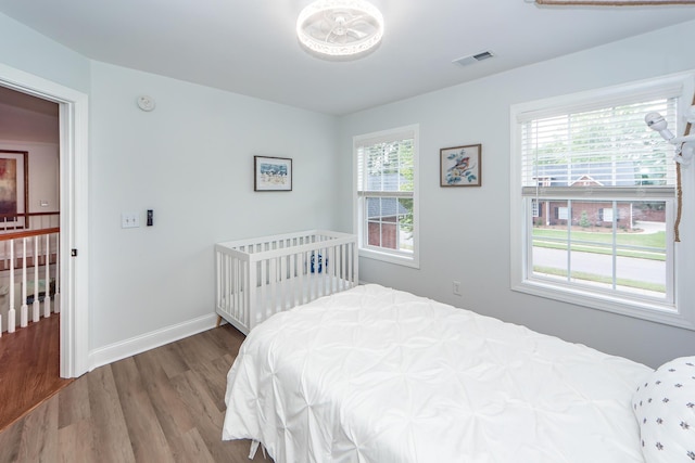 bedroom featuring baseboards, wood finished floors, and visible vents