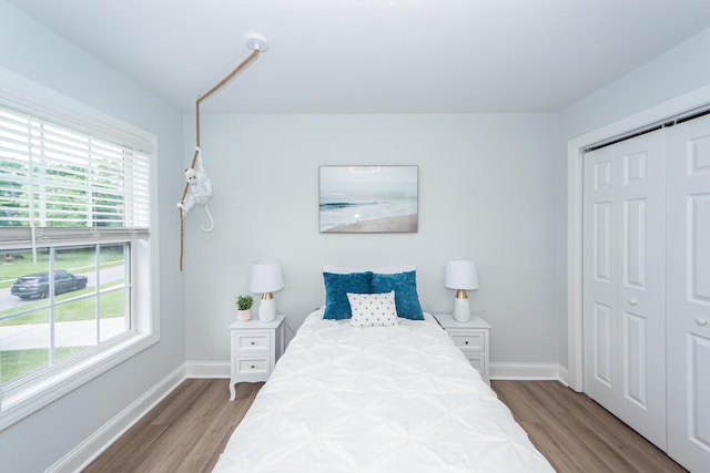 bedroom with baseboards, multiple windows, and wood finished floors