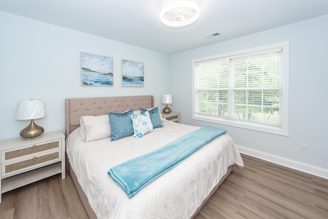 bedroom with visible vents, baseboards, and wood finished floors