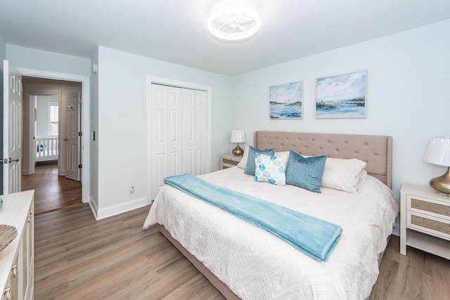 bedroom featuring baseboards, light wood-style floors, and a closet
