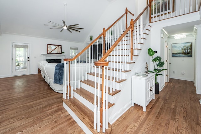 stairs with a fireplace, wood finished floors, a ceiling fan, and baseboards