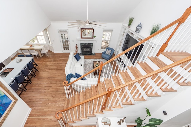 stairs featuring wood finished floors, a fireplace, and ceiling fan