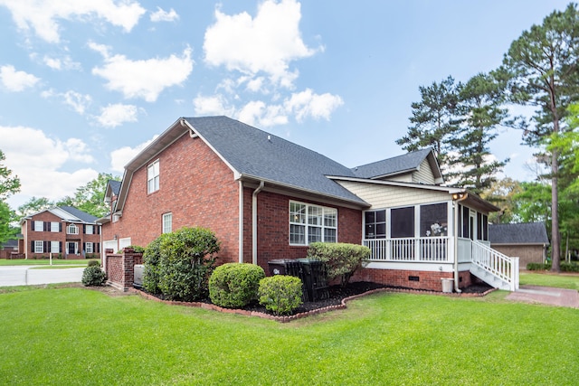 view of side of home featuring roof with shingles, brick siding, a lawn, a sunroom, and crawl space