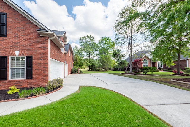 view of property exterior featuring brick siding, driveway, a yard, and a garage