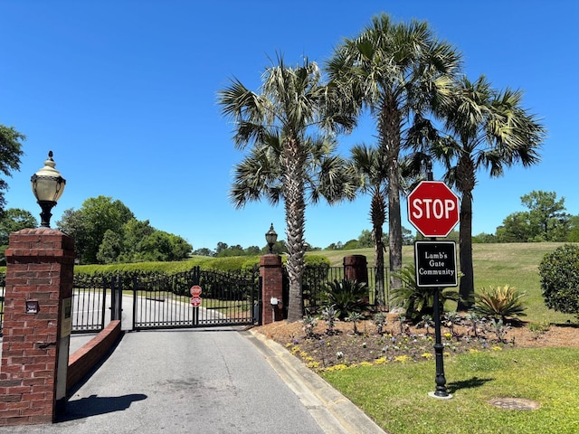 view of street featuring a gated entry, street lighting, a gate, and traffic signs