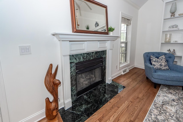 living room featuring a fireplace, wood finished floors, built in features, and baseboards