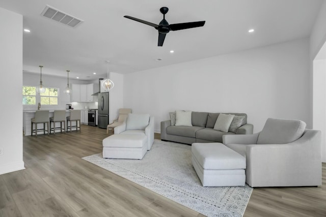 living room with ceiling fan and light hardwood / wood-style floors