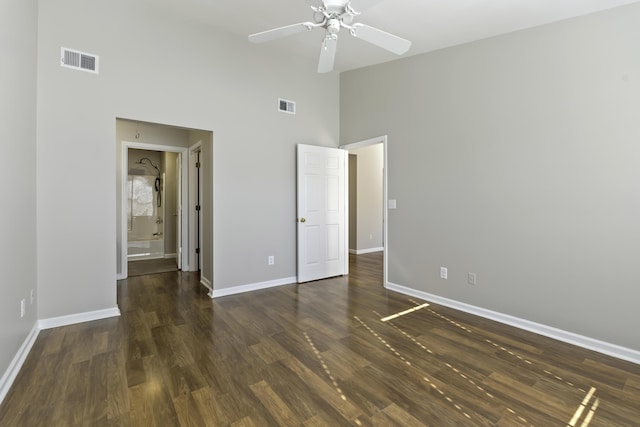 unfurnished bedroom with ceiling fan, dark hardwood / wood-style flooring, and a towering ceiling