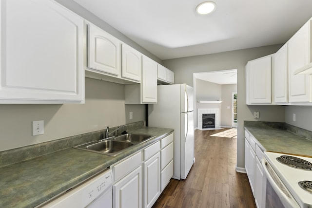 kitchen featuring a tile fireplace, white cabinetry, sink, and dark wood-type flooring