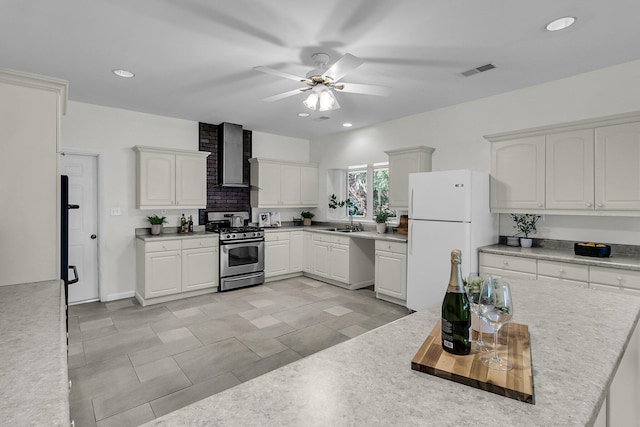 1085 Harts Bluff Rd, Wadmalaw Island, SC 29487 - kitchen featuring stainless steel gas range, freestanding refrigerator, wall chimney exhaust hood, ceiling fan, and light countertops