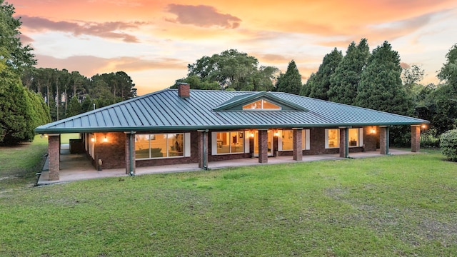 1085 Harts Bluff Rd, Wadmalaw Island, SC 29487 - back of property at dusk with a standing seam roof, a metal roof, and a lawn