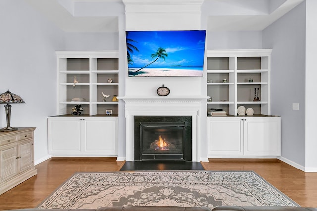living room with a fireplace with flush hearth, wood finished floors, and baseboards