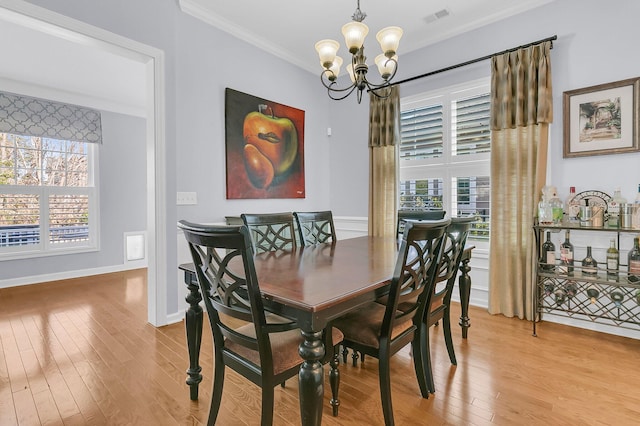 dining area with light wood finished floors, plenty of natural light, a chandelier, and ornamental molding