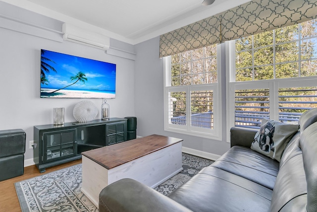 living room featuring an AC wall unit, baseboards, and wood finished floors